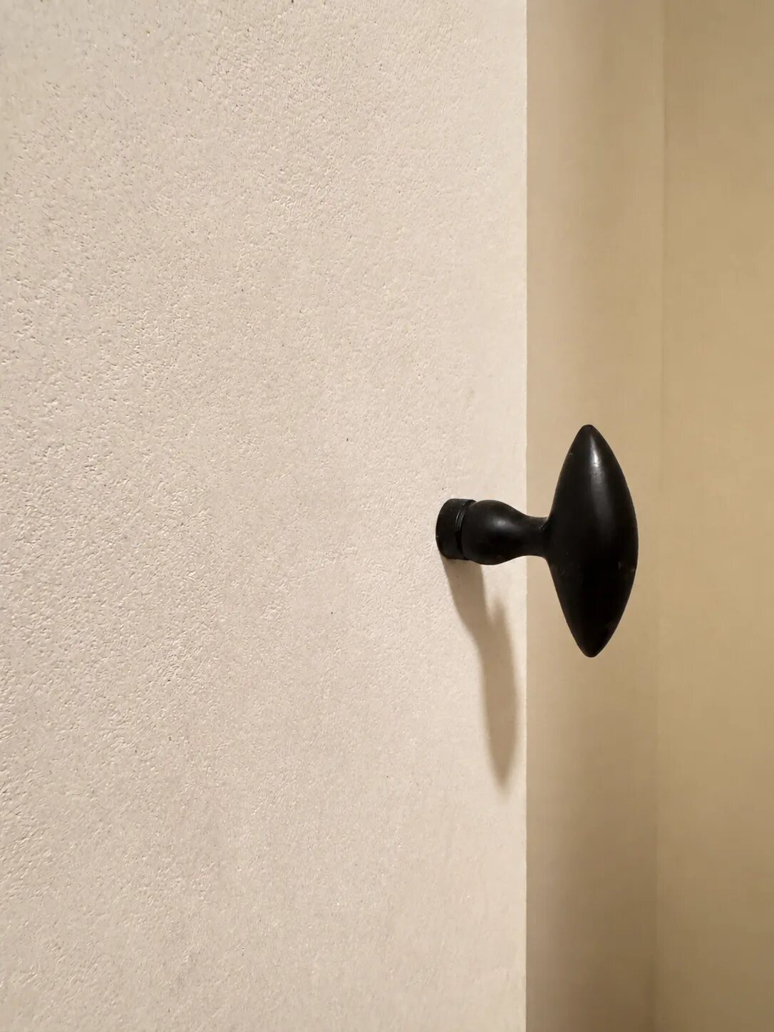 Black door knob against a matte Tadelakt wall at Róhe